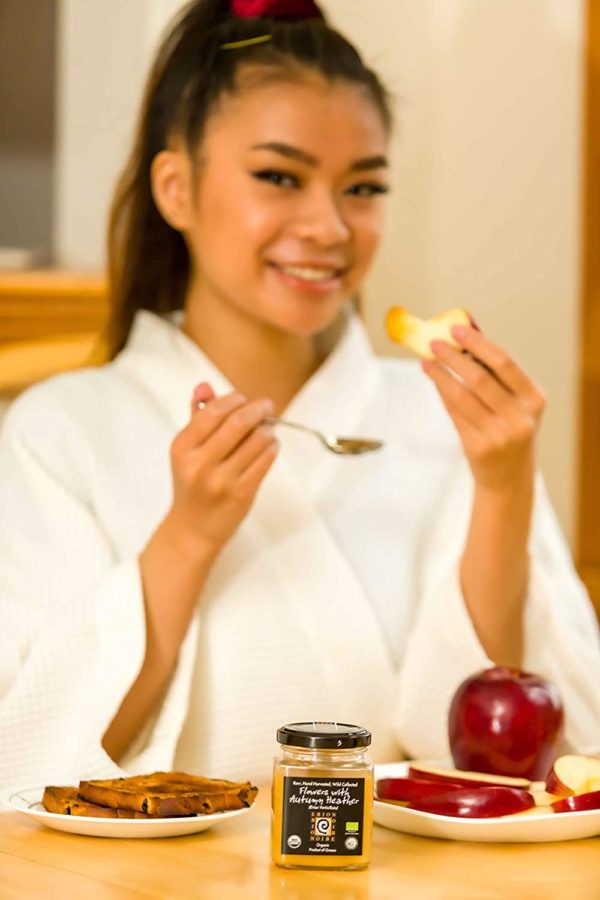Woman eating honey with a spoon.